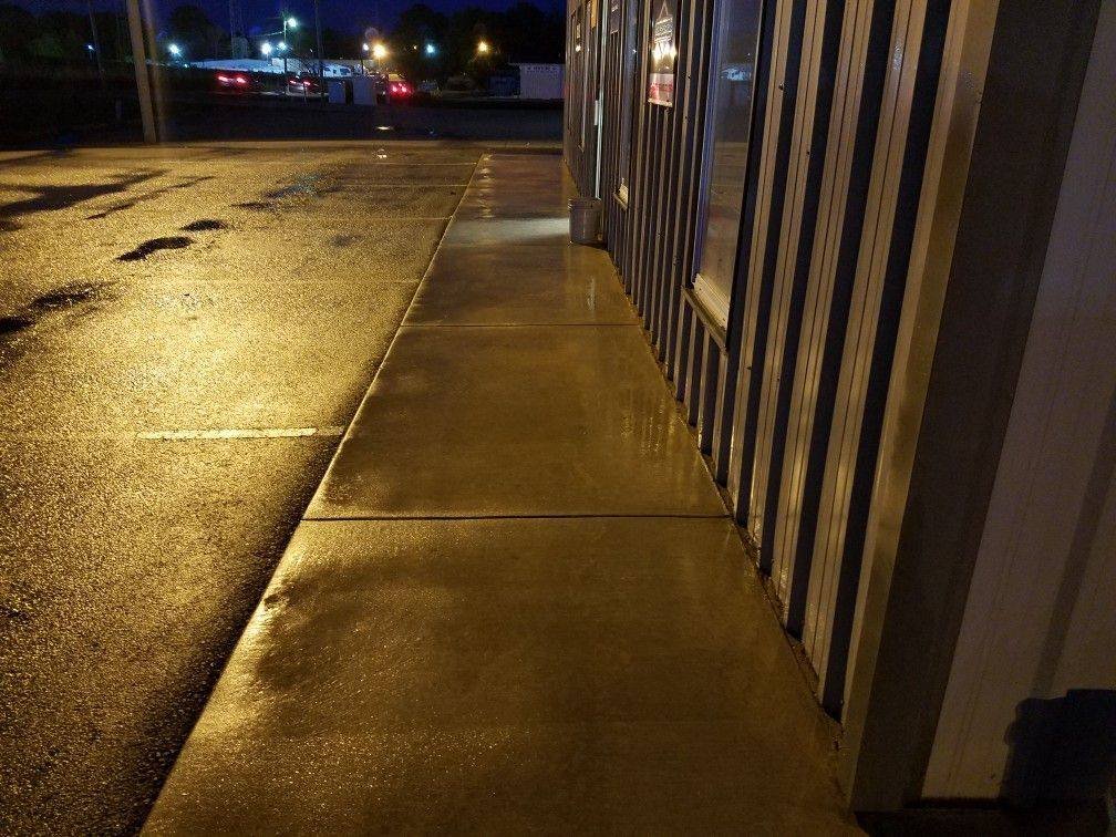 Freshly pressure-washed commercial storefront sidewalk at night