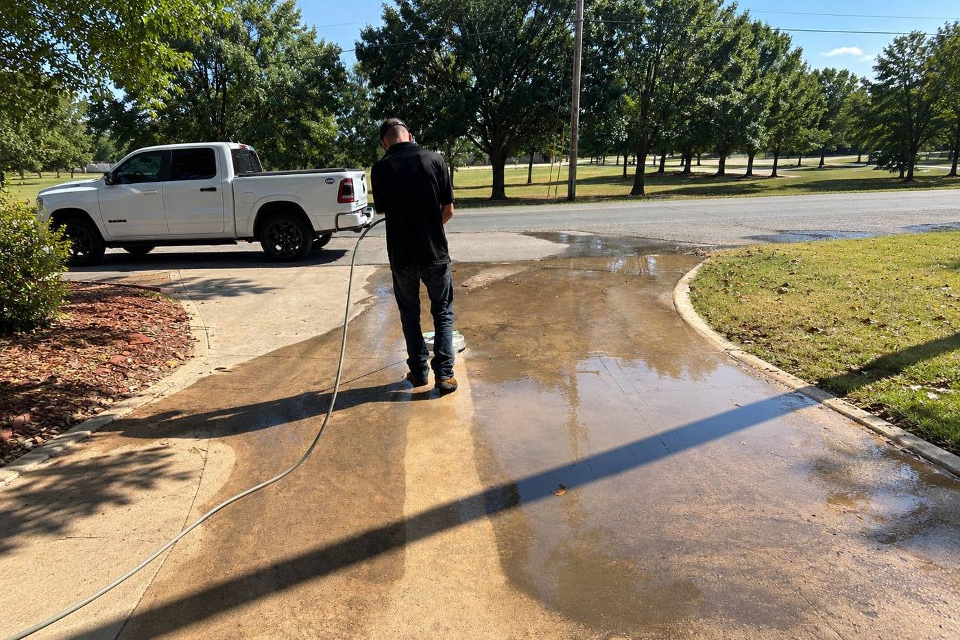 Crew member surface-cleaning a stained concrete driveway