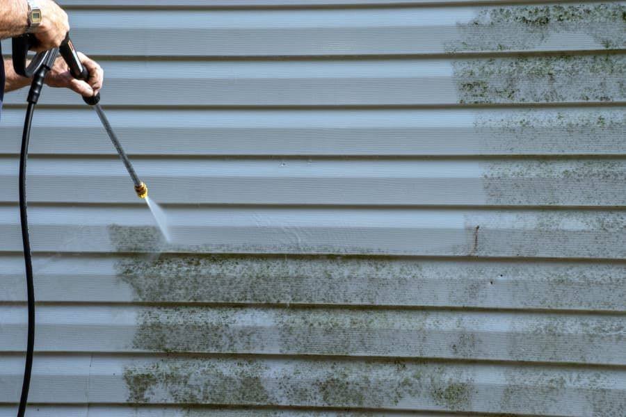 Vinyl siding half cleaned, showing mildew removed by washing